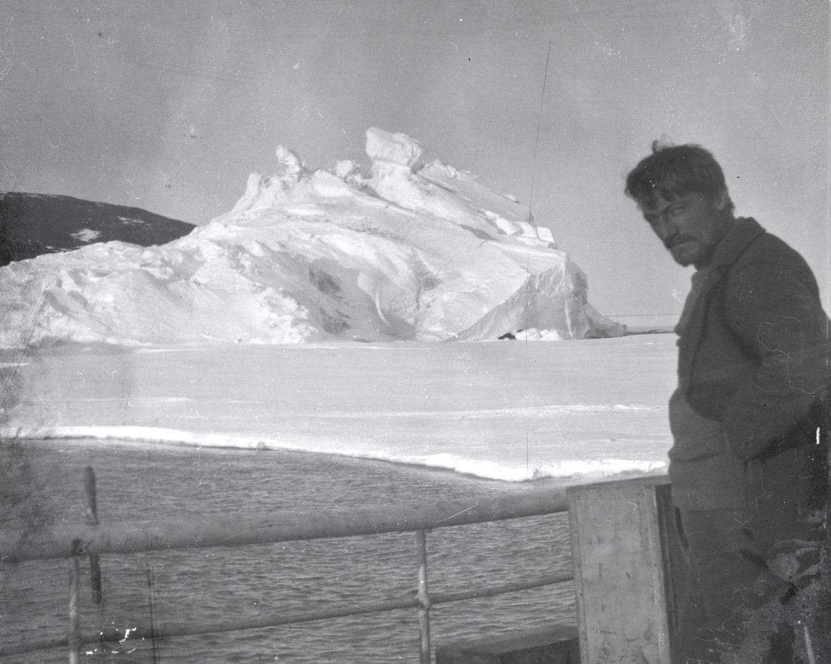 A black and white image of a young, bearded man, Alexander Stevens, aboard a ship in the Antarctic.